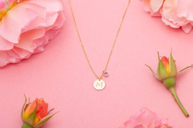 Still life jewelry picture for online sale. Photo of a silver necklace on a pink floral background that we can use in e-commerce, online sales, and social media.