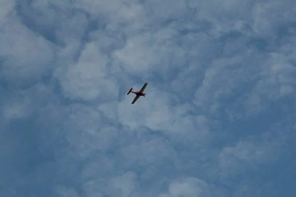 plane in the sky full of cattered clouds