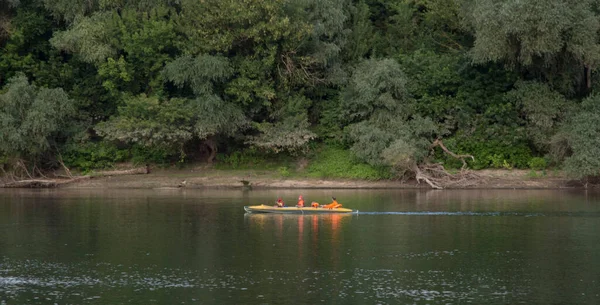 four people in an orange air boat sailing in the middle of a river