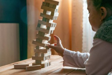 Masa oyunu oynayan şirin küçük kız, tahta bloklardan kule inşa ediyor..