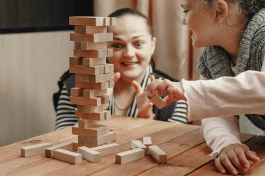 Anne ve kızı tahta bloklardan bir kule inşa etmek için masa oyunu oynuyorlar..