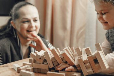 Anne ve kızı tahta bloklardan bir kule inşa etmek için masa oyunu oynuyorlar..