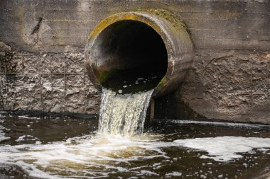 Dirty water flows from the pipe into the river, environmental pollution. Sewerage, treatment facilities. clipart