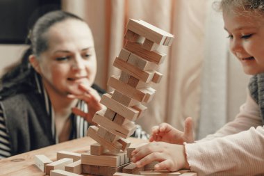 Anne ve kızı tahta bloklardan bir kule inşa etmek için masa oyunu oynuyorlar..