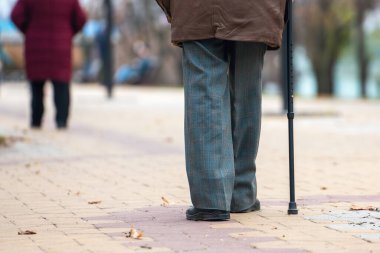Sokakta bastonla yürüyen yaşlı bir adamın bacakları..