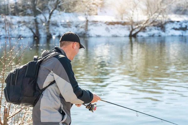 早春的时候 一位渔夫带着钓竿和背包在白雪覆盖的河岸上钓鱼 — 图库照片