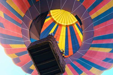 Gökyüzüne yükselen sepetli çok renkli sıcak hava balonu..