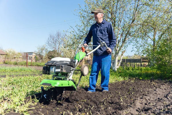 農家の男は播種のための土壌を準備する耕運機で土地を耕す — ストック写真