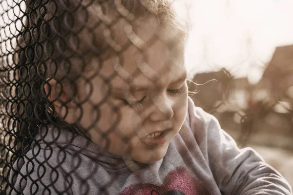 金属製の柵の後ろに悲しい表情をした少女 ロシアに占領された地域からのウクライナの子供の強制送還の問題 — ストック写真