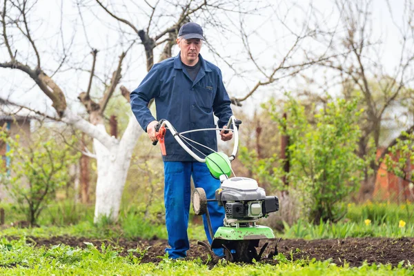 農家の男は播種のための土壌を準備する耕運機で土地を耕す — ストック写真