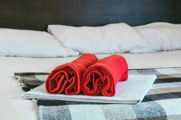 Red towels rolled up lie on the bed in the room.