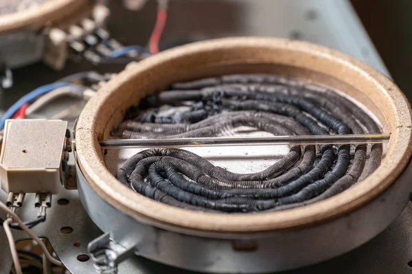 Disassembled electric burner with burned out heating elements, wires and cables.