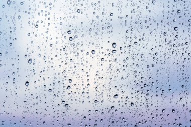 Raindrops on window glass, cloudy weather, background texture