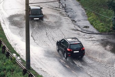 Driving a car through a large puddle after heavy rain.