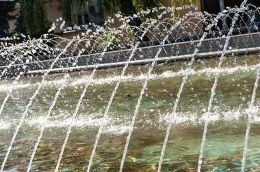 Çeşmenin fıskiyeleri yaz güneşinde gümüşle parıldıyor..