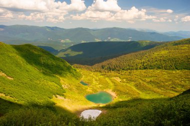 Two small lakes in the canyon of the Carpathian Mountains, on a sunny day, against the background of a blue sky with white clouds