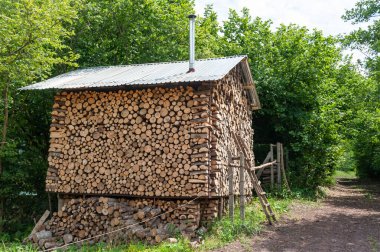 The forest hut of Grandma Yaga. It has no windows, no doors, and there is a chimney. A country house drowning in the green of the forest trees, the walls of which are lined from bottom to top with logs of chopped firewood.