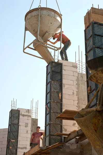 Çok katlı bir binanın gelecekteki sütunlarına beton harç dökülüyor.