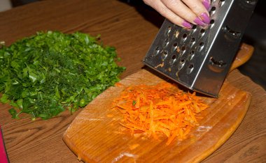 Kesilmiş yeşil maydanoz ve kurutmak için metal rendesine kırmızı biber sürüyorum.