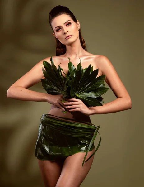 fashion magazine model poses in clothes made of natural elements, green leaves, spring concept