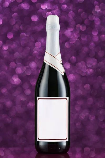 Wine bottle with blank white label on a crystal table. Abstract purple background with bokeh effect