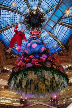 Paris, Fransa - 12 04 2021: Kozmonot gibi giyinmiş Noel Baba, Lafayette Haussmann 'ın oldukça renkli Noel ağacının etrafında yürüyor