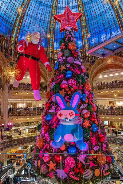 Paris, Fransa - 12 04 2021: Kozmonot gibi giyinmiş Noel Baba, Lafayette Haussmann 'ın oldukça renkli Noel ağacının etrafında yürüyor