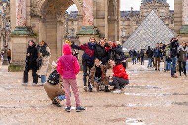 Paris, Fransa - 12 04 2021: Bir grup gülümseyen genç turist kız Atlı Süvari Zafer Kemeri önünde selfie çekiyorlar