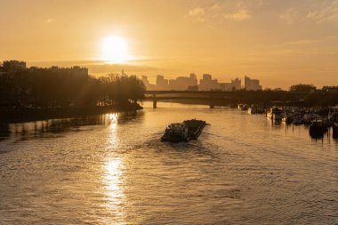 Sen Nehri 'nin rıhtımları. Clichy Köprüsü 'nden gün batımında Seine ve Savunma Bölgesi boyunca yelken açan bir mavnanın görüntüsü.