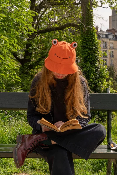 Una Joven Sentada Banco Leyendo Libro Con Sombrero Naranja Forma — Foto de Stock