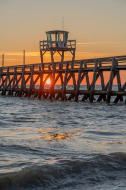 View of a wooden pier in front of the sea, a colorful sunrise and Le Havre city buildings far away