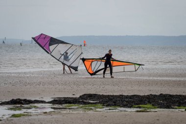 Windsurfer preparing his sail's sailboard on the beach