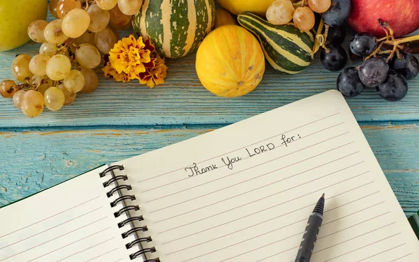 A handwritten text in an open notebook. Thank You, LORD. Fall fruits on wood table. The biblical concept of thankfulness and thanksgiving to God and Jesus Christ. Grateful Christian praise and worship.