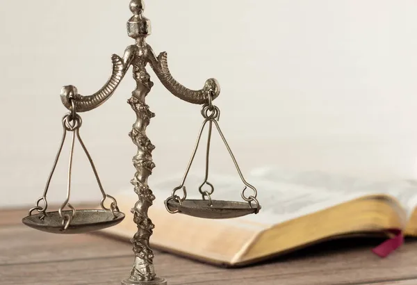 Hukuk ve adalet, İncil 'deki Hristiyan kavramı. Eski çağlardan kalma tartı terazisi beyaz arka planlı kutsal kitap ile dengelenmiş. Yüce İsa, Yargı Günü 'nde adil bir yargıçtır. Yakın çekim..