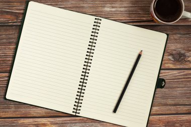 Kalemle birlikte boş spiral bir defter aç ve tahta masa arkasında bir fincan kahve olsun. Üst Manzara. Uzayı metin için kopyala. İş konsepti.