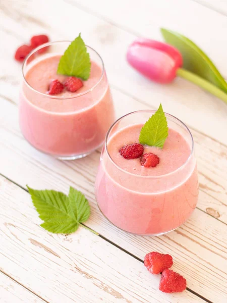 粉红色的覆盆子 放在木制桌子上的杯子里 上面有新鲜的叶子和覆盆子 早餐或甜点时喝健康的水果饮料 基于植物的食品和饮料概念 — 图库照片