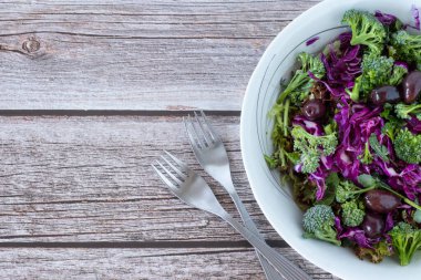Kırmızı lahanalı, brokolili, zeytinli ve çatallı marullu taze sebze salatası. Sağlıklı bitki temelli yeme kavramı.