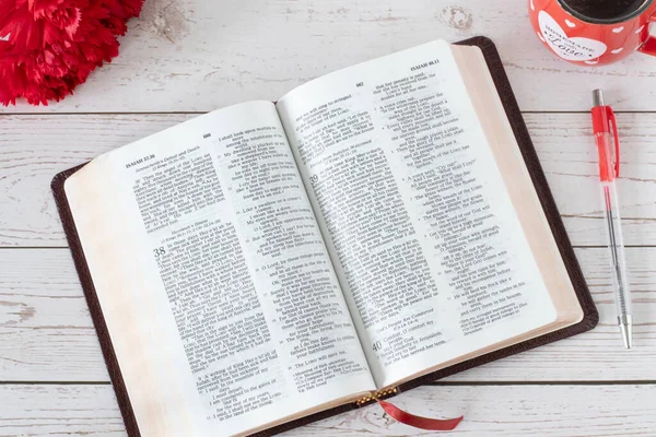 新鮮な赤い花と木のテーブルの上に暖かいコーヒーカップで聖書の本を開きます トップビュー クローズアップ 聖書の神のことばの読み書きの概念イエス キリスト — ストック写真