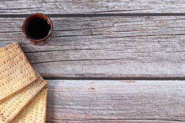 Mayasız ekmek (matzo) ve bir bardak şarap kopyalanmış ahşap masa üzerinde. Üst manzara, düz yatış. Hristiyan bayramı bayramı kutlaması. İsa 'nın günahları için yaptığı fedakarlık İncil' deki kavram.