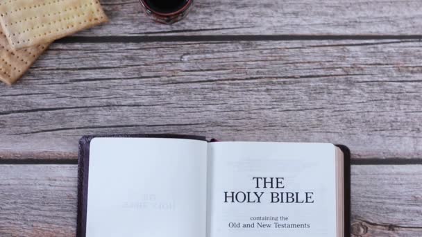 无酵面包和一杯葡萄酒与圣经书放在木桌上 顶部视图 基督教逾越节新遗嘱的圣经概念 复制空间 — 图库视频影像