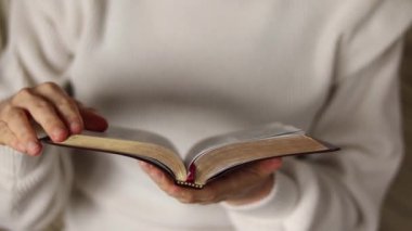 Genç Hıristiyan kadın elinde altın sayfalarla dolu kutsal bir kitap tutuyor. Tanrı 'dan bilgelik ve bilgi arayışında. İsa Mesih' in inancından. İncil konseptinden öğreniyorum. Yakın plan..