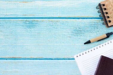 Kapalı kutsal kitap, boş defter ve fotokopi alanı olan ahşap bir masa üzerindeki kalem. Üst manzara, düz yatış. Okuma, okuma ve kutsal metinler yazma. Hıristiyan eğitimi, İncil kavramı.