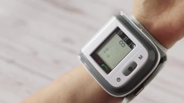 Evdeki bir insan kolundaki dijital monitörle tansiyon ölçümü. Kalp atışını ölçmek için elektronik cihaz. Yakın çekim..