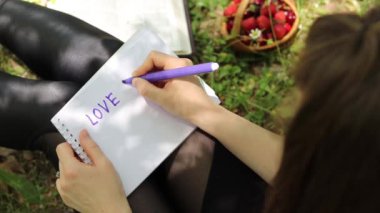 Genç bir kız elinde bir defter tutuyor ve doğasında 