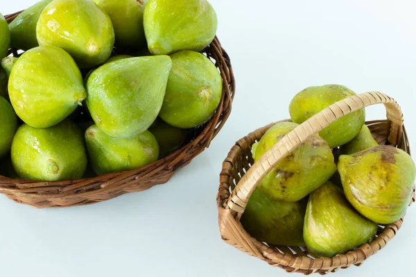Ripe figs in two wicker baskets isolated on a white background. Good and bad fig fruit. A close-up. Top table view.
