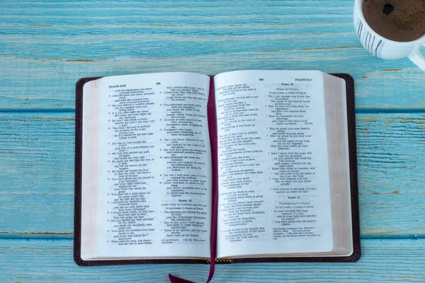 Otwórz Biblię Świętą Filiżanką Kawy Niebieskim Drewnianym Tle Widok Stolik — Zdjęcie stockowe