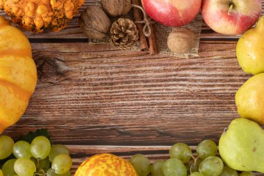 Sonbahar arkaplanı, balkabağı, elma, üzüm ve ahşap masada çeşitli sonbahar meyveleri. Uzayı kopyala Üst görünüm.