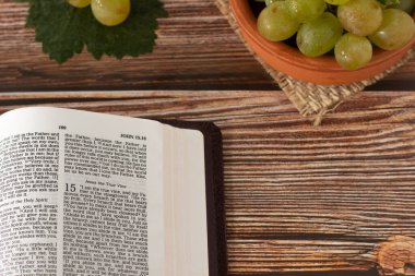 Kutsal Kitap 'ı aç. Olgunlaşmış üzümlerle birlikte ahşap bir masaya yerleştirilmiş, üzerinde fotokopi alanı olan bir kasede. Hıristiyan İncili kavramı.