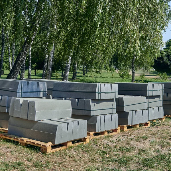 Sınır. Topakların ve çimenlerin üzerinde yığılmış sınırlar. Paletler beton kaldırımlı. Kaldırımın onarımı.