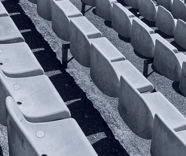 スタジアムのグランドスタンド席の行 錆びたプラスチック製の白いスタジアムの座席 白黒写真 — ストック写真